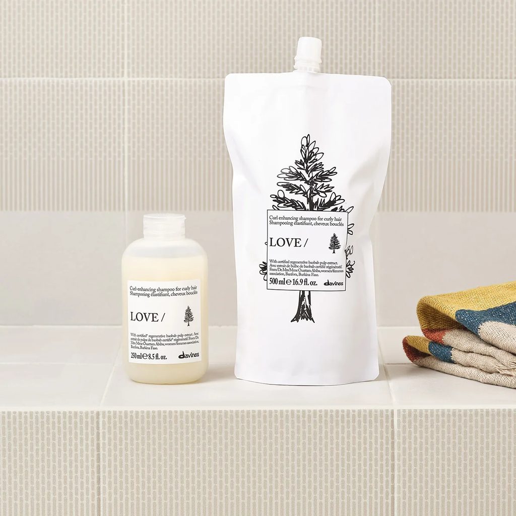 Bottle and pouch with 'LOVE' text and tree design on a neutral background
